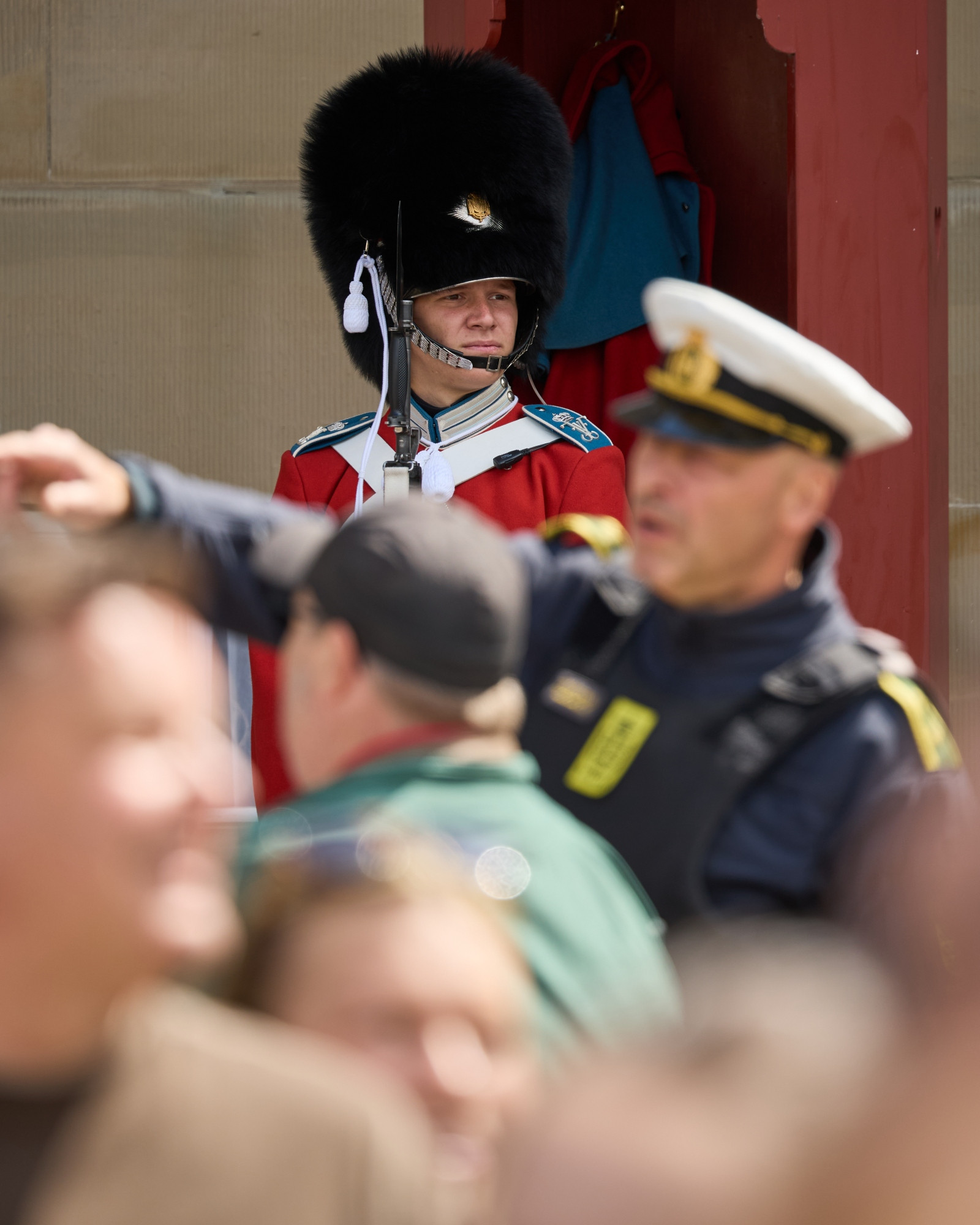 King Frederik's Birthday at Amalienborg Castle in Copenhagen. A member of the Royal Guard in red gala and police officer guiding the crowd.